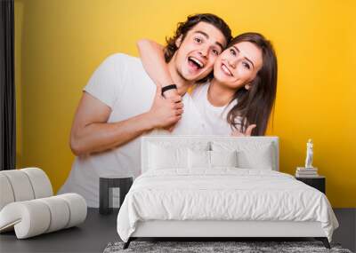 Young couple posing together while making selfie and woman showing thumb up, over yellow background Wall mural